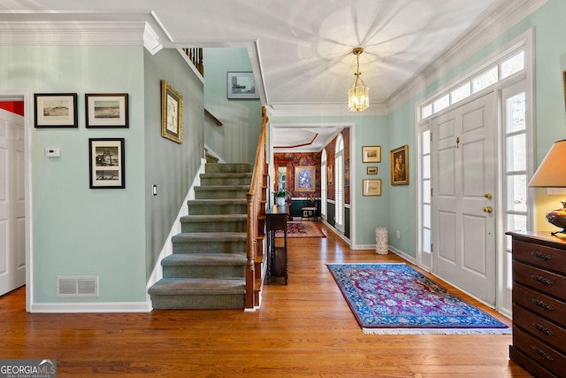 foyer with visible vents, crown molding, baseboards, stairs, and wood finished floors