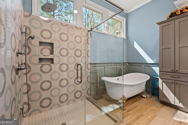 full bath featuring a wainscoted wall, ornamental molding, a wealth of natural light, tiled shower, and a decorative wall