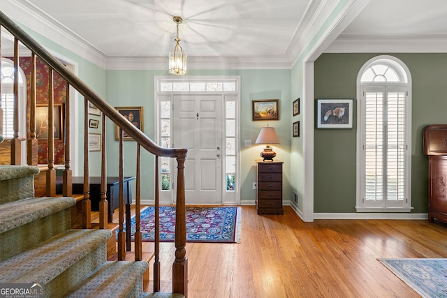 entryway with wood finished floors, stairs, and ornamental molding