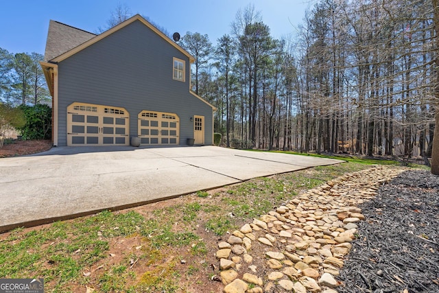 view of side of property featuring a garage and roof with shingles