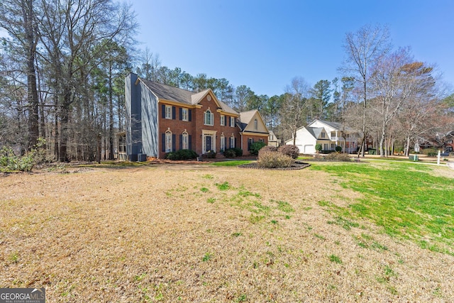 view of front of home featuring brick siding, a chimney, and a front yard