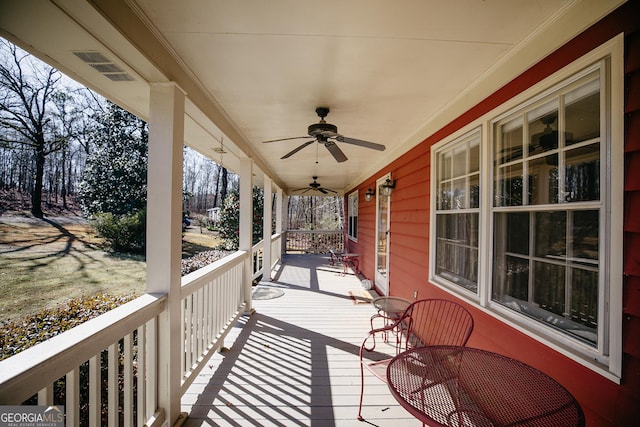 wooden terrace with visible vents, covered porch, and a ceiling fan