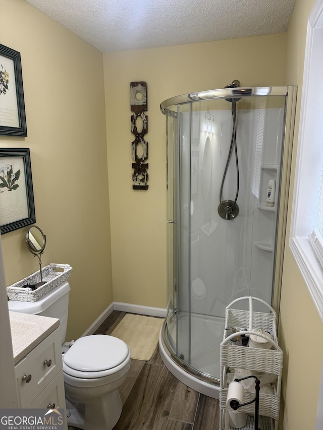 bathroom with vanity, wood finished floors, a stall shower, and a textured ceiling