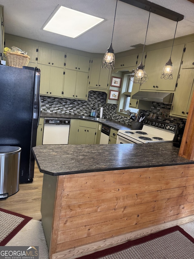 kitchen featuring under cabinet range hood, white appliances, dark countertops, and a peninsula