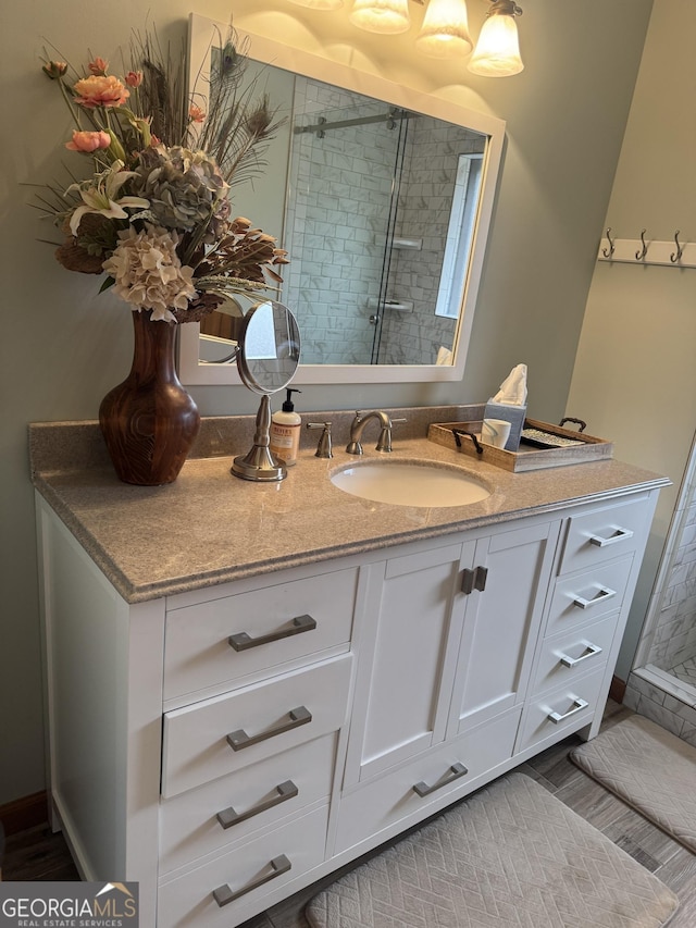 bathroom featuring tiled shower and vanity