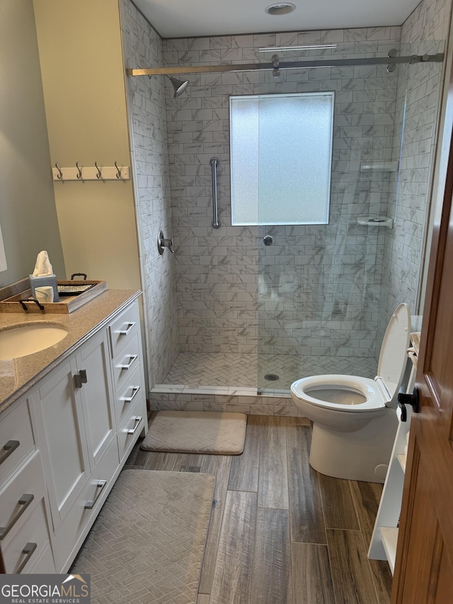 full bathroom featuring vanity, toilet, wood finished floors, and a stall shower