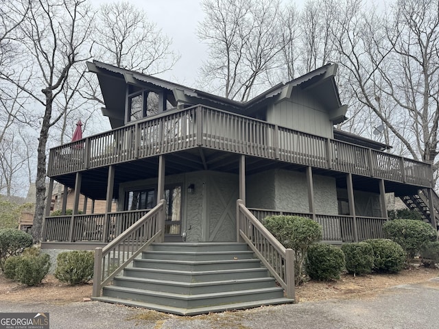 view of front facade featuring stairway, a deck, and stucco siding