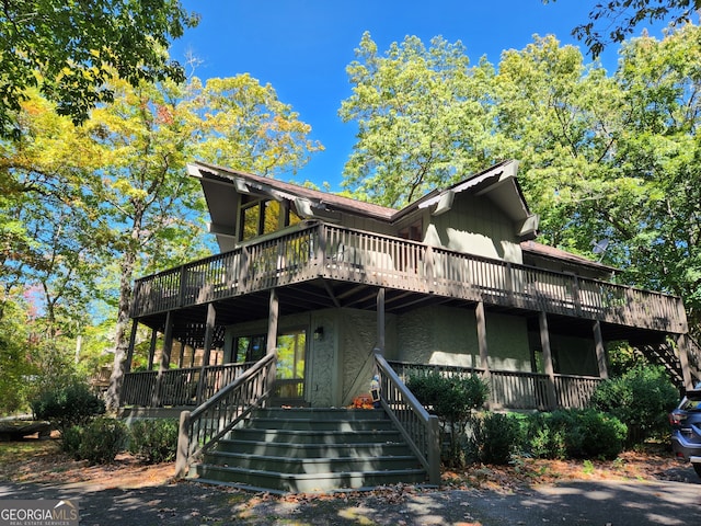 view of front of home featuring stucco siding, a wooden deck, and stairs