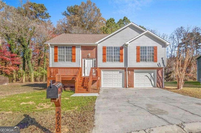 split foyer home featuring a front lawn, a garage, brick siding, and aphalt driveway