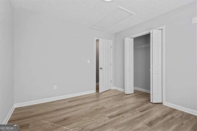 unfurnished bedroom featuring wood finished floors, baseboards, and a closet