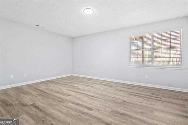 empty room featuring wood finished floors, baseboards, and a textured ceiling