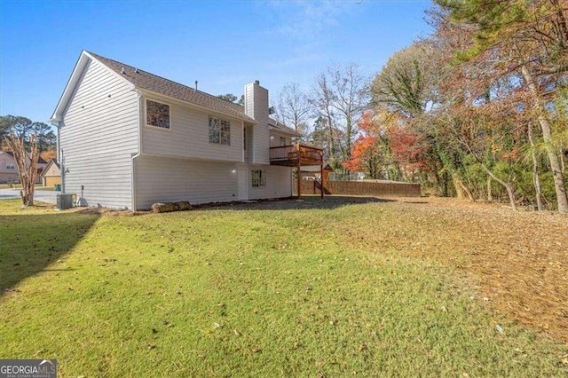 exterior space with a wooden deck, cooling unit, a chimney, and a yard