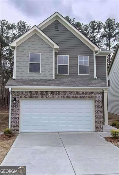 traditional home with a garage, brick siding, and concrete driveway