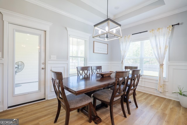 dining room featuring a tray ceiling, a healthy amount of sunlight, and light wood-style flooring