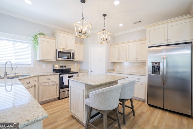 kitchen featuring light wood-style flooring, a sink, a center island, appliances with stainless steel finishes, and crown molding