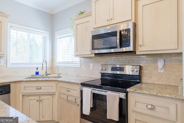 kitchen with a sink, stainless steel appliances, light stone countertops, and ornamental molding