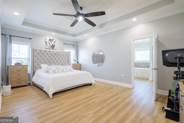 bedroom featuring a tray ceiling, multiple windows, and light wood-style flooring