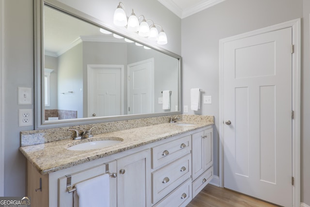 bathroom with crown molding, wood finished floors, double vanity, and a sink