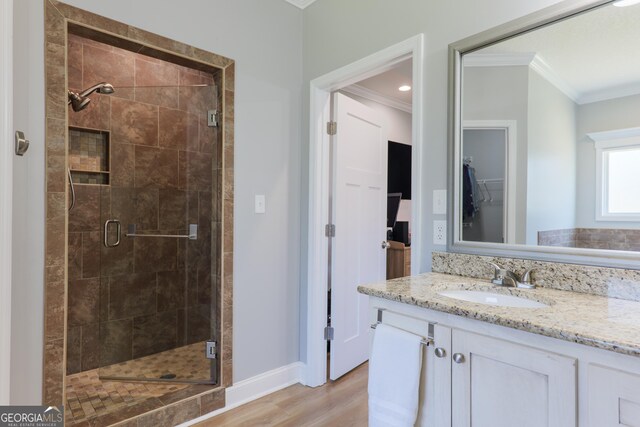 bathroom featuring wood finished floors, a shower stall, crown molding, baseboards, and vanity