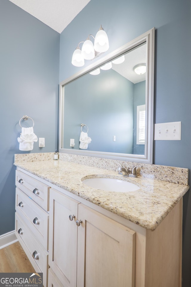 bathroom with baseboards, wood finished floors, and vanity