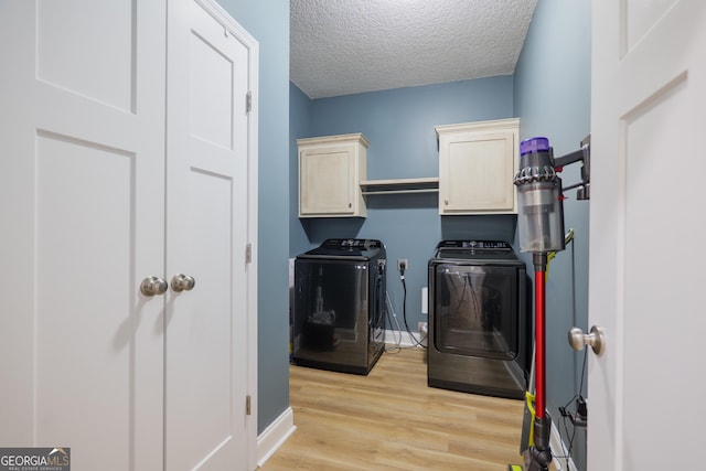 laundry room with baseboards, light wood-type flooring, washer and dryer, cabinet space, and a textured ceiling