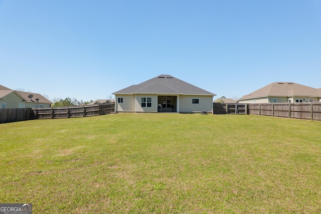 rear view of house with a yard and a fenced backyard