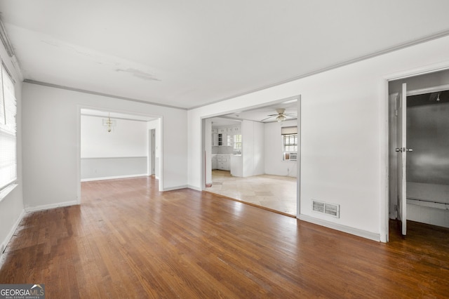 empty room featuring visible vents, a ceiling fan, baseboards, and hardwood / wood-style flooring