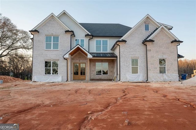 view of front of home featuring brick siding, french doors, and a standing seam roof