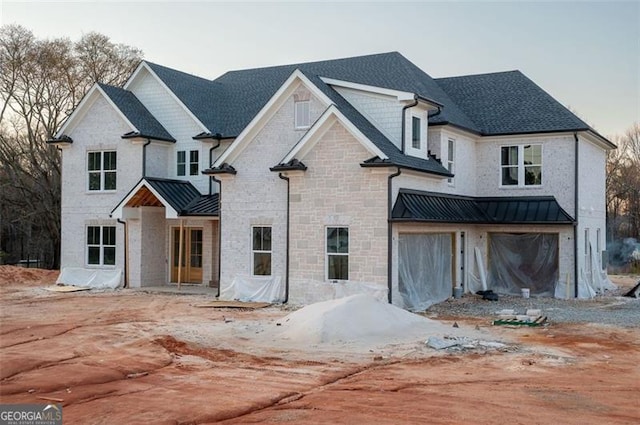 view of front of house featuring a standing seam roof, stone siding, roof with shingles, and metal roof