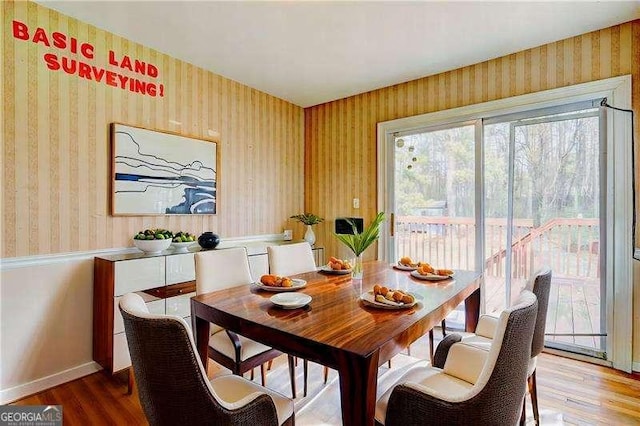 dining area with wallpapered walls, baseboards, and wood finished floors