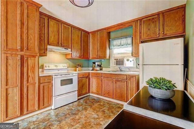 kitchen with white appliances, brown cabinetry, light countertops, and under cabinet range hood