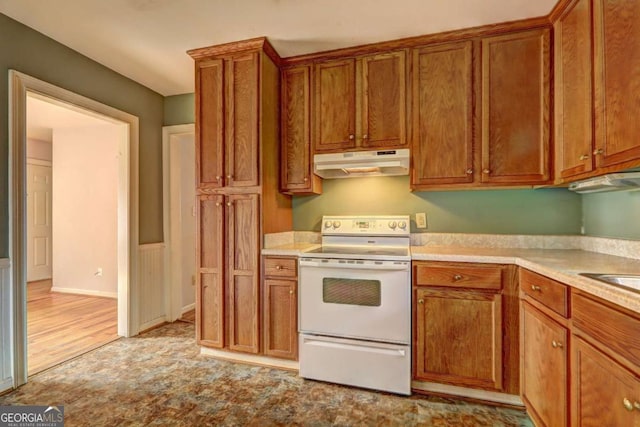 kitchen with light countertops, electric range, brown cabinetry, and under cabinet range hood