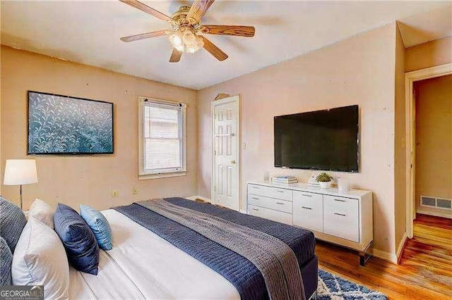 bedroom with ceiling fan, visible vents, baseboards, and wood finished floors