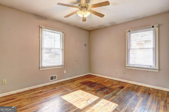 unfurnished room featuring a wealth of natural light, a ceiling fan, and wood-type flooring