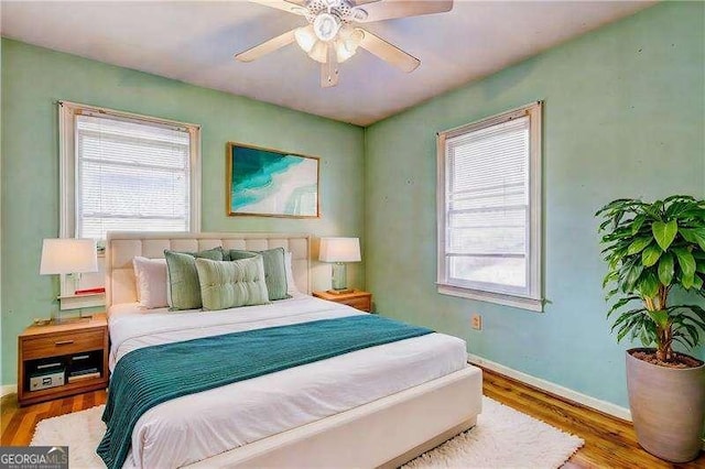 bedroom featuring multiple windows, wood finished floors, and baseboards