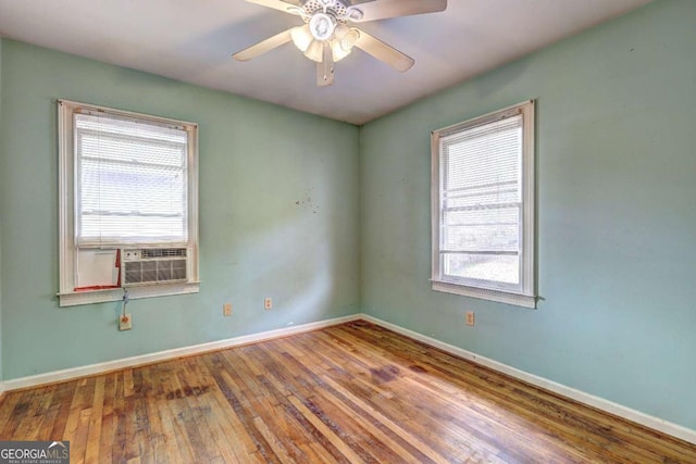 spare room featuring cooling unit, a ceiling fan, baseboards, and wood-type flooring