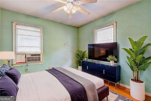 bedroom featuring cooling unit, wood finished floors, baseboards, and ceiling fan