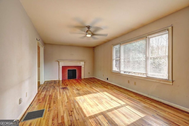 unfurnished living room featuring a wealth of natural light, visible vents, wood finished floors, and a ceiling fan