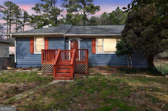 ranch-style house with a deck and fence