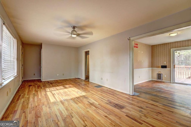 spare room featuring baseboards, wood finished floors, and a ceiling fan