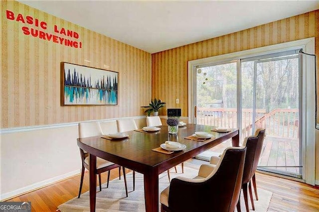 dining area featuring wallpapered walls, baseboards, and light wood-type flooring