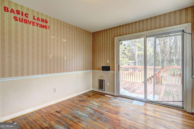 unfurnished room with wallpapered walls, baseboards, and wood-type flooring