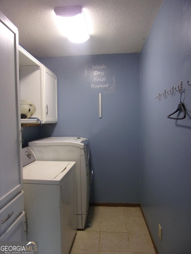 laundry room featuring independent washer and dryer, a textured ceiling, cabinet space, light tile patterned floors, and baseboards