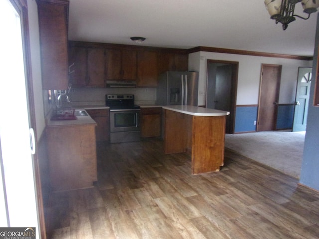 kitchen featuring wood finished floors, a kitchen island, a sink, stainless steel appliances, and under cabinet range hood