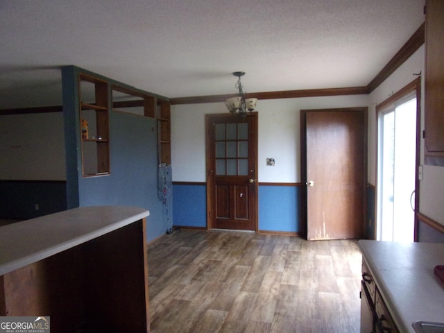 unfurnished dining area featuring ornamental molding, wood finished floors, and a chandelier