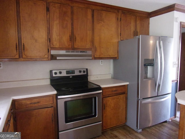 kitchen with under cabinet range hood, appliances with stainless steel finishes, brown cabinetry, and light countertops