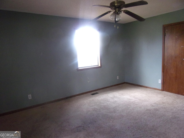 carpeted empty room with visible vents, ceiling fan, and baseboards