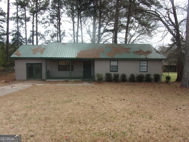 single story home with a front yard, covered porch, and metal roof