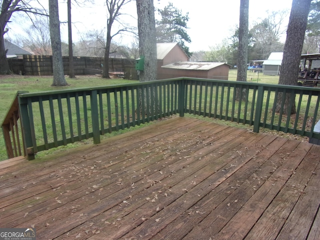 deck with an outbuilding, a lawn, and a fenced backyard