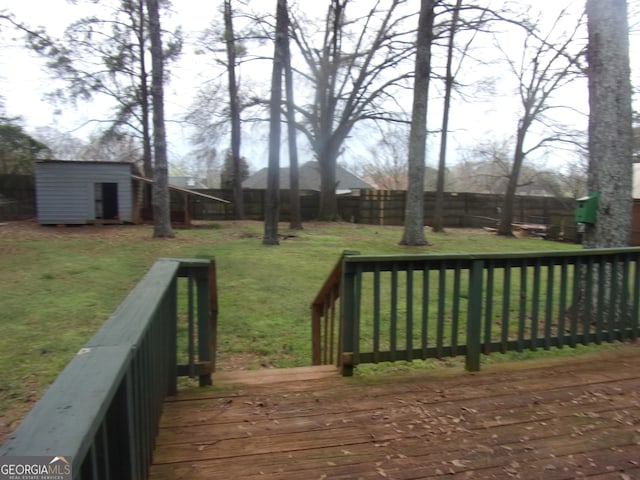 deck with a storage unit, an outbuilding, a fenced backyard, and a yard